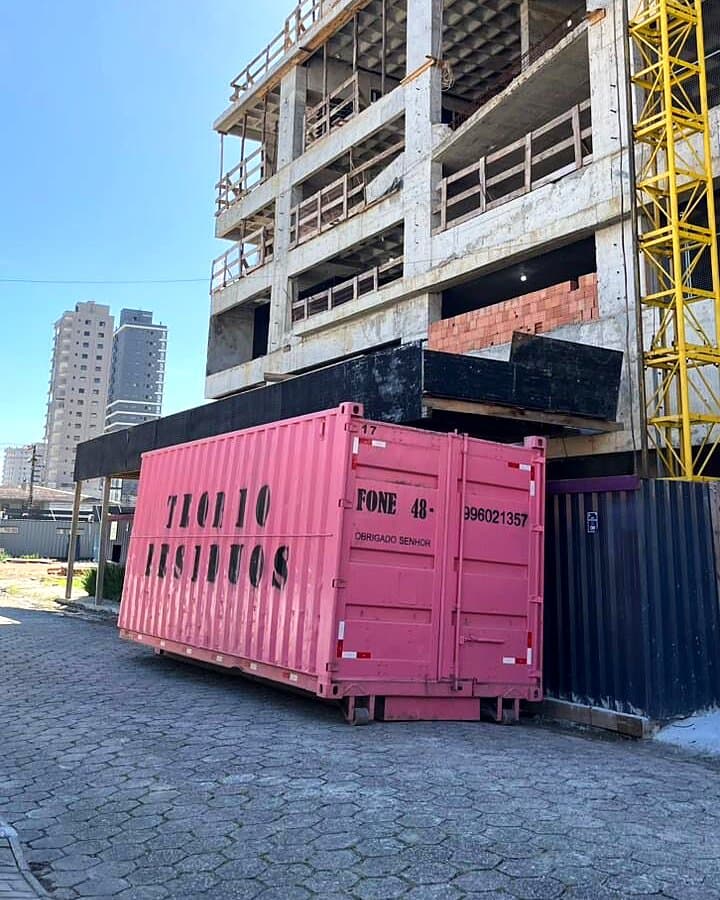 Caçamba rosa da Teqbio Resíduos na calçada de um prédio em construção