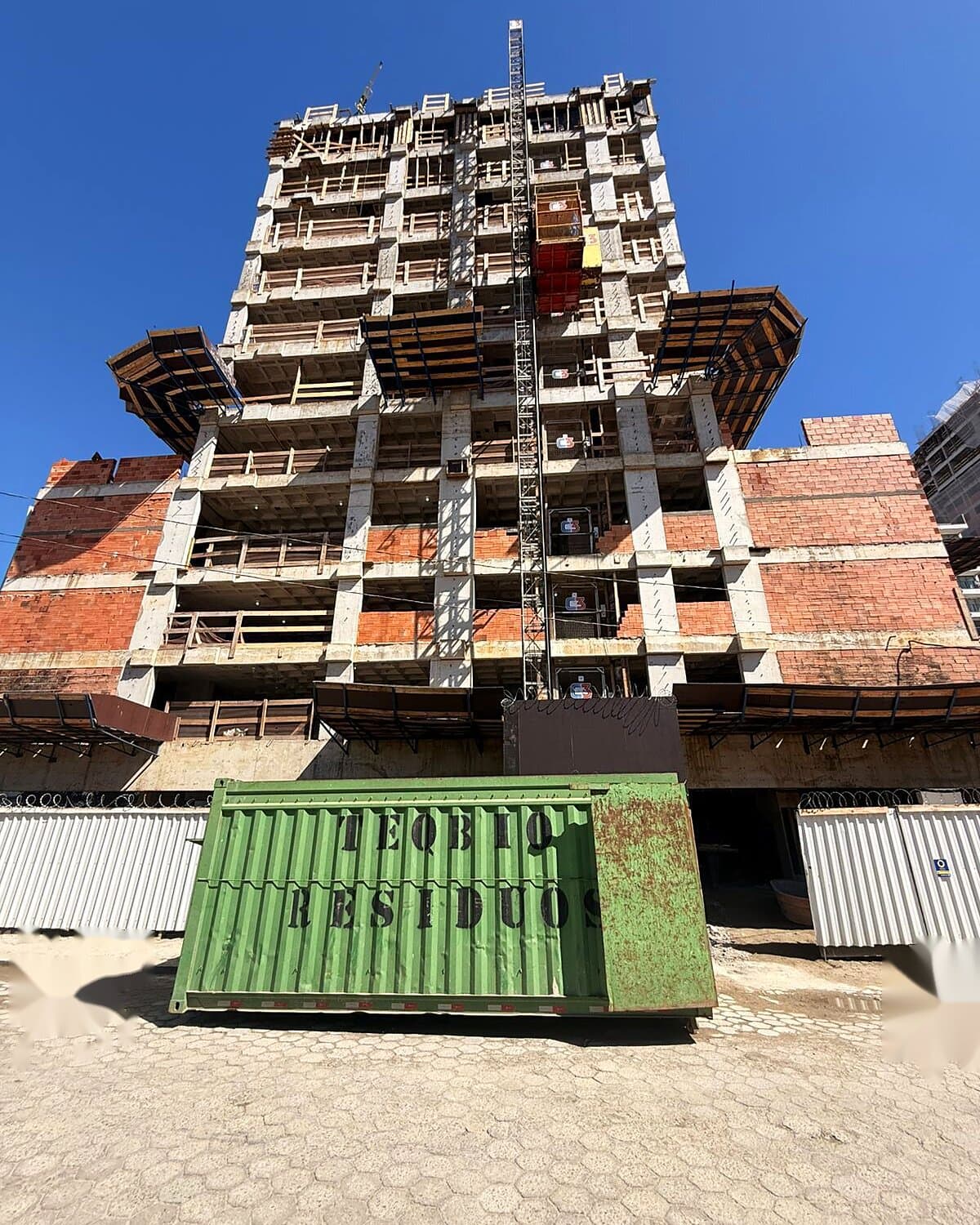 Caçamba verde da Teqbio em frente a torre residencial em construção